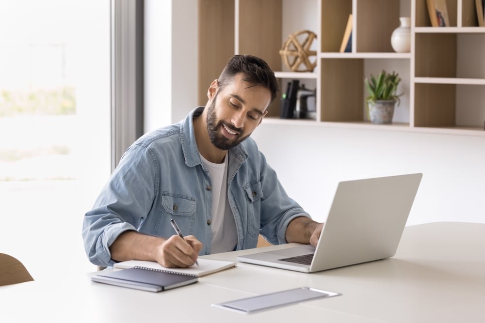 Ondernemer maakt notities tijdens online werk met laptop.
