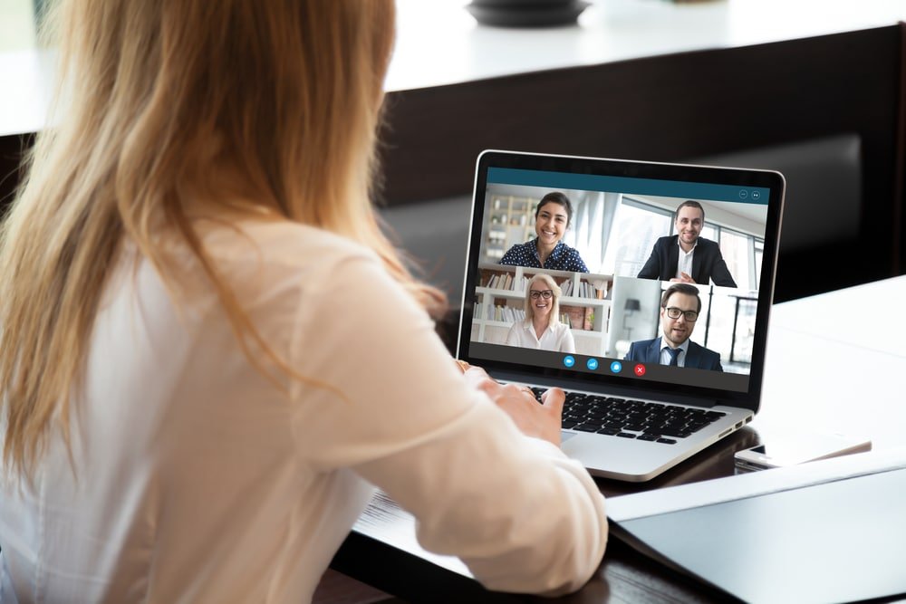 Vrouw neemt deel aan online vergadering via laptop met meerdere collega’s.