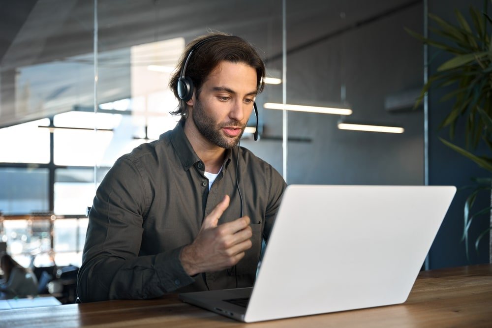 Zakelijke professional in videogesprek met headset en laptop.