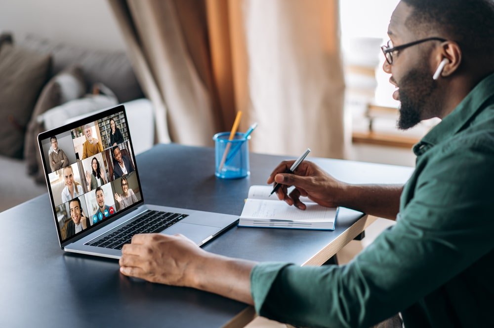 Man neemt deel aan groepsvideocall en maakt notities.